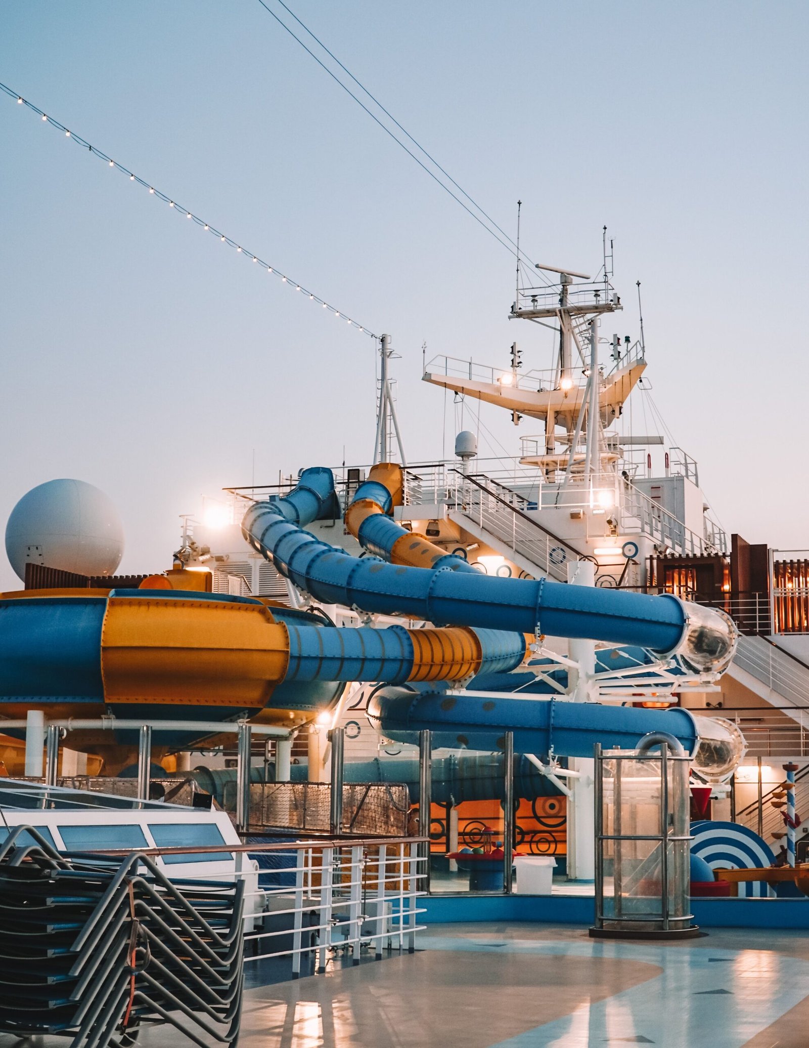 A vibrant scene of water slides on a cruise ship at sunset, showcasing leisure and travel.