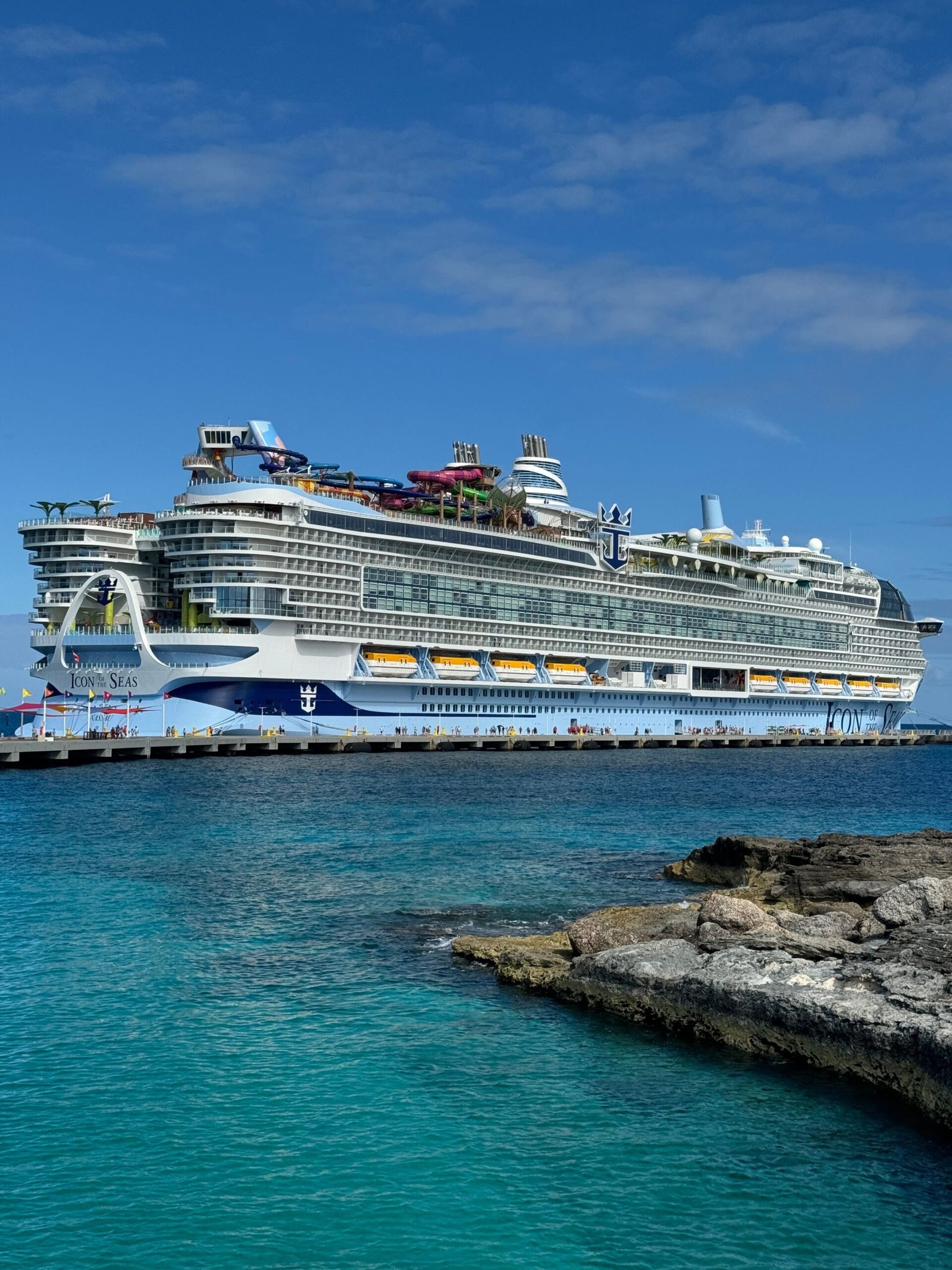 Majestic cruise ship docked at a rocky coastline under clear blue skies, perfect for vacationers.