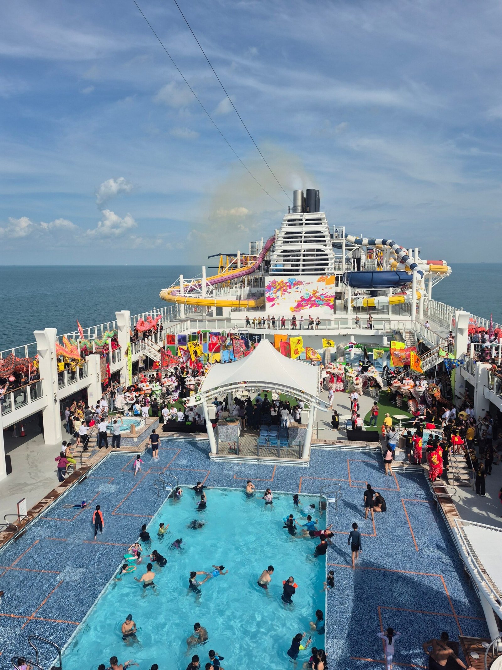 A lively cruise ship deck with a bustling pool area and ocean views, perfect for vacations.